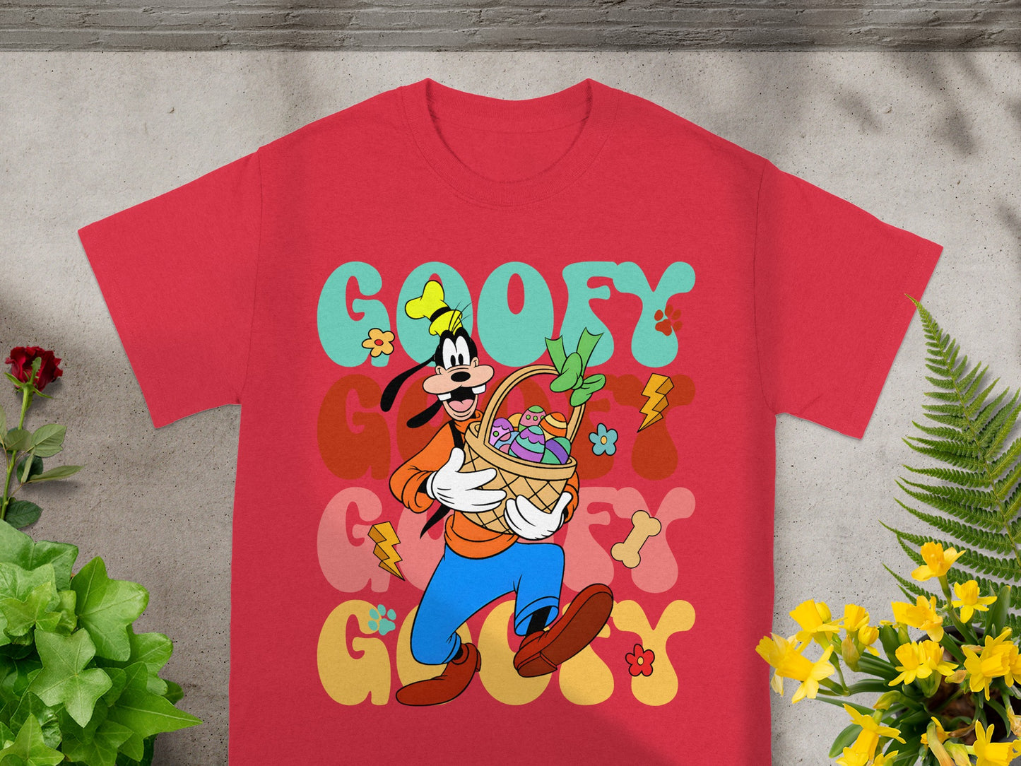 Red t-shirt with Goofy holding an Easter basket, featuring colorful text and floral graphics.
