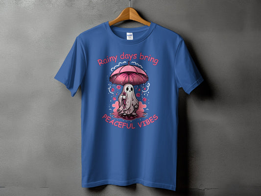 Blue t-shirt with a cartoon ghost under an umbrella, text "Rainy days bring peaceful vibes".