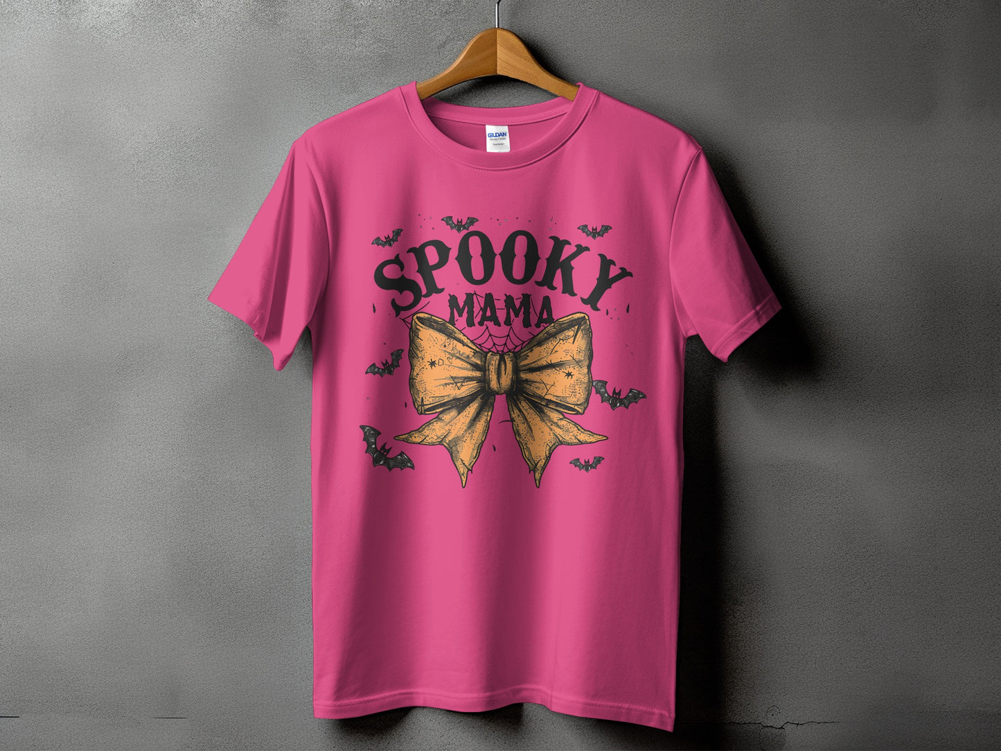 Pink t-shirt with "Spooky Mama" text, bats, and a bow graphic.