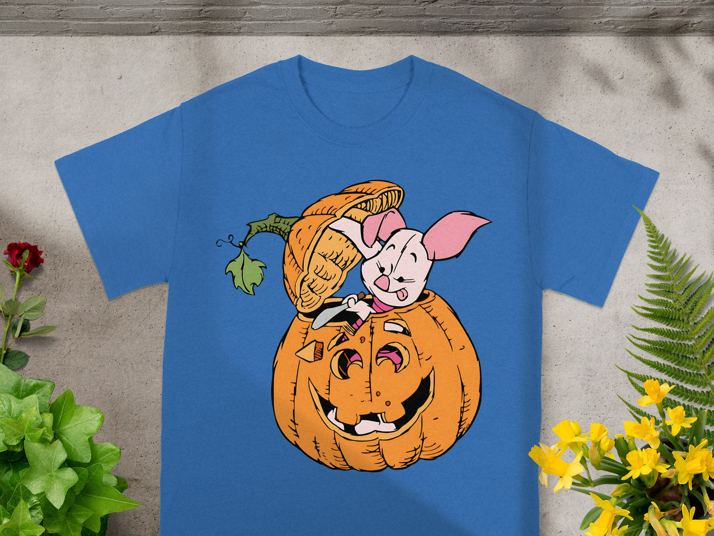 Piglet peeks out of a carved Halloween pumpkin on a blue t-shirt.