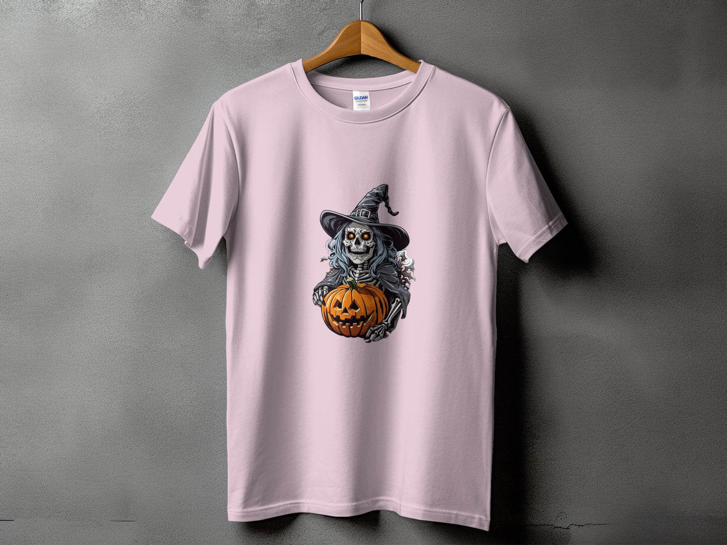 Pink t-shirt with a skeleton wearing a witch hat holding a jack-o'-lantern.