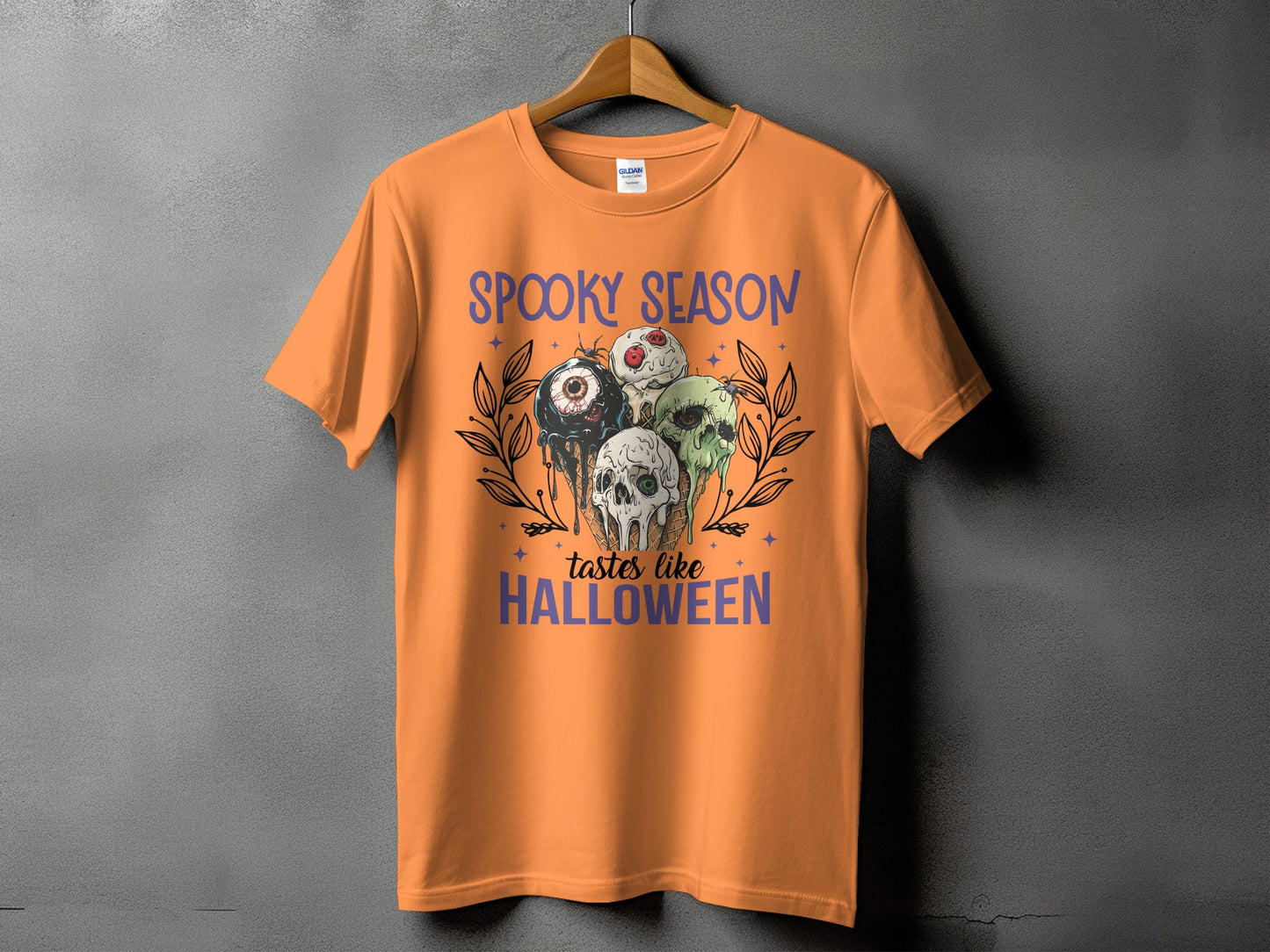 Orange t-shirt with "Spooky Season Tastes Like Halloween" text and creepy ice cream graphic.