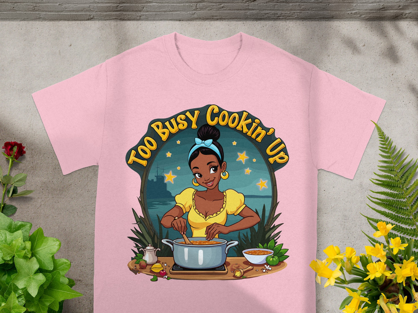 Pink t-shirt with "Too Busy Cookin' Up" graphic of a woman cooking.