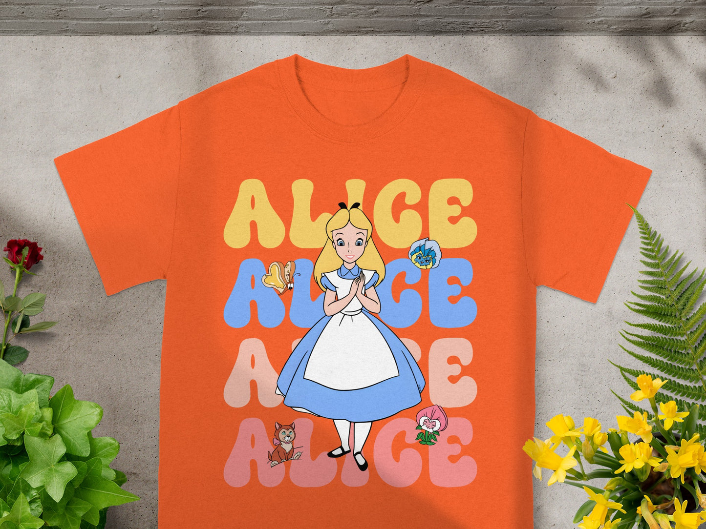 Orange t-shirt with Alice in Wonderland graphic and colorful text.