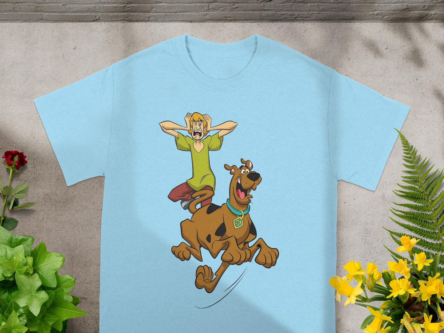 Scooby-Doo and Shaggy running from a monster on a light blue t-shirt.
