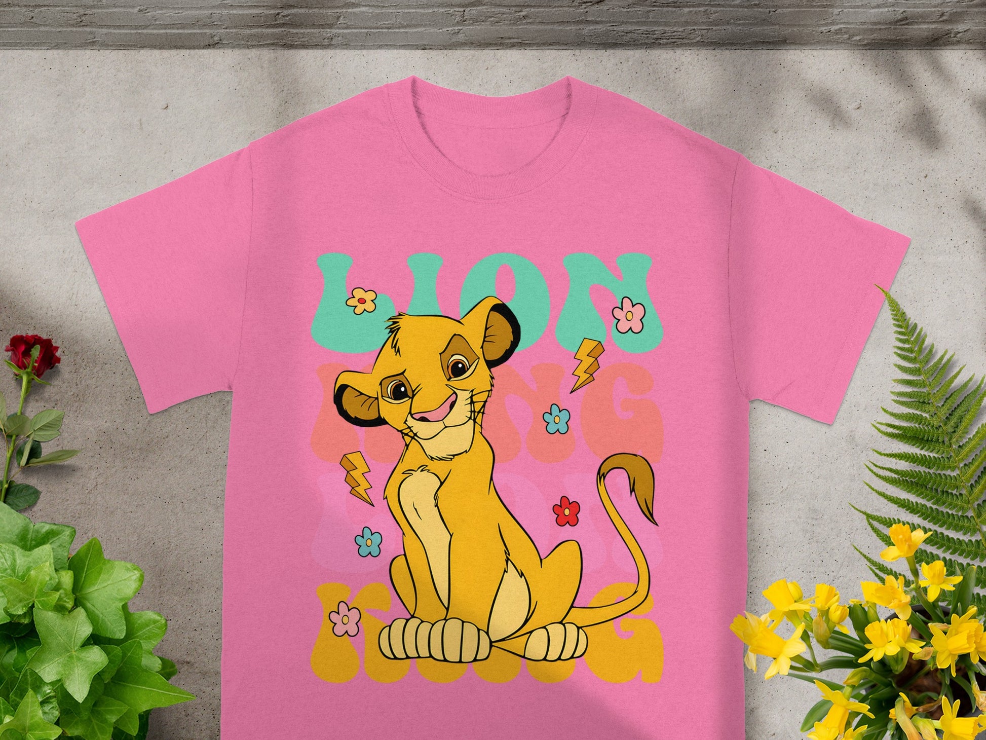 Simba from The Lion King on a pink t-shirt with flowers and lightning bolts.