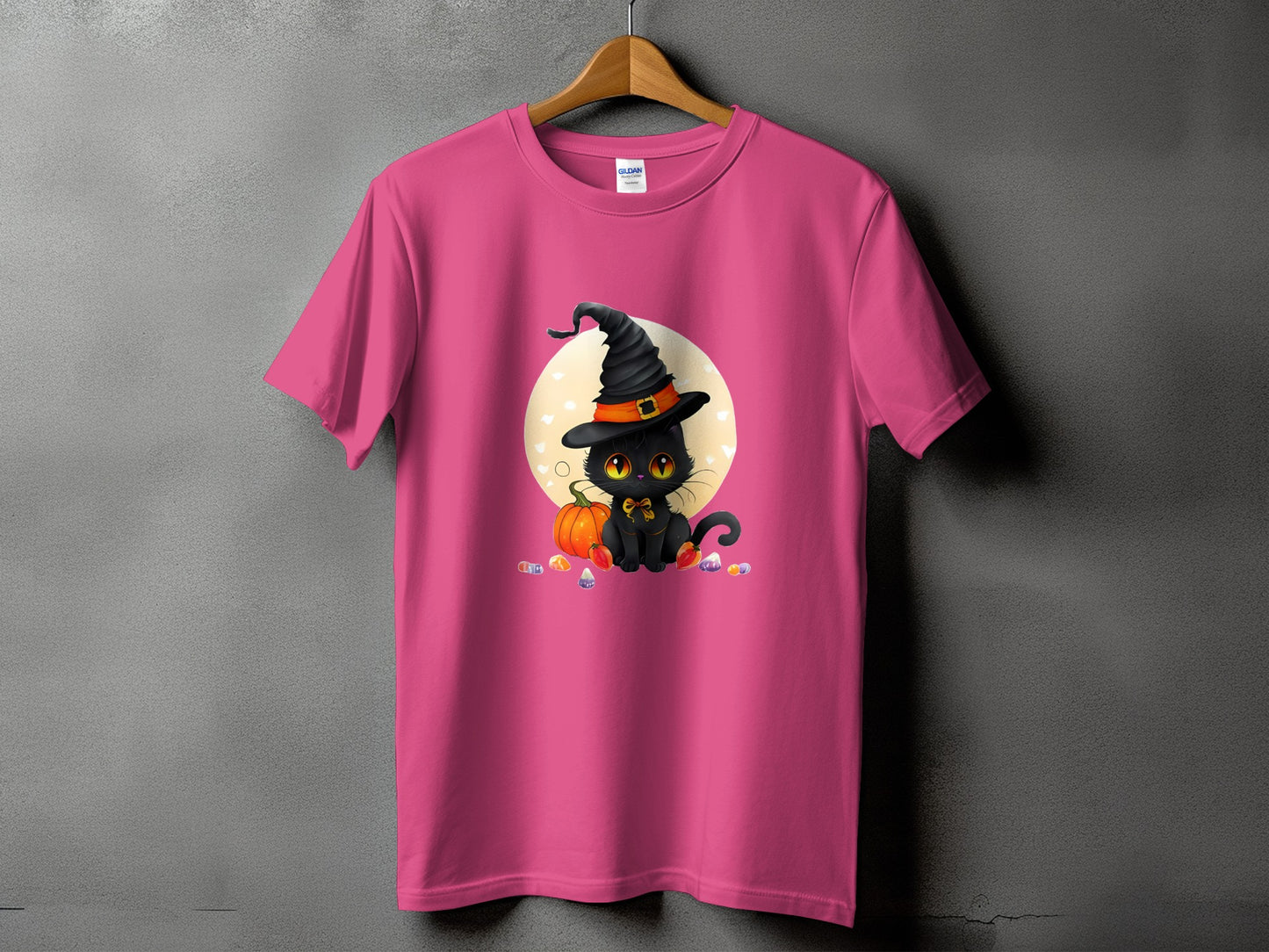 Pink t-shirt with a black cat wearing a witch hat and surrounded by candy.