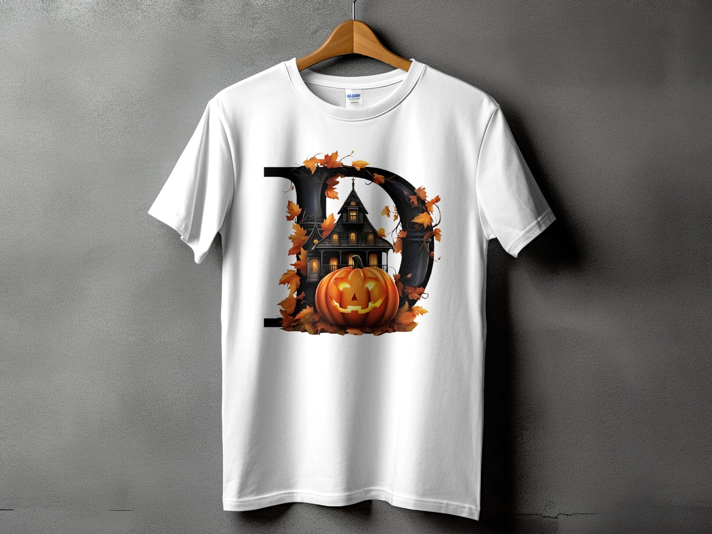 White t-shirt with a black letter D, haunted house, pumpkin, and autumn leaves graphic.