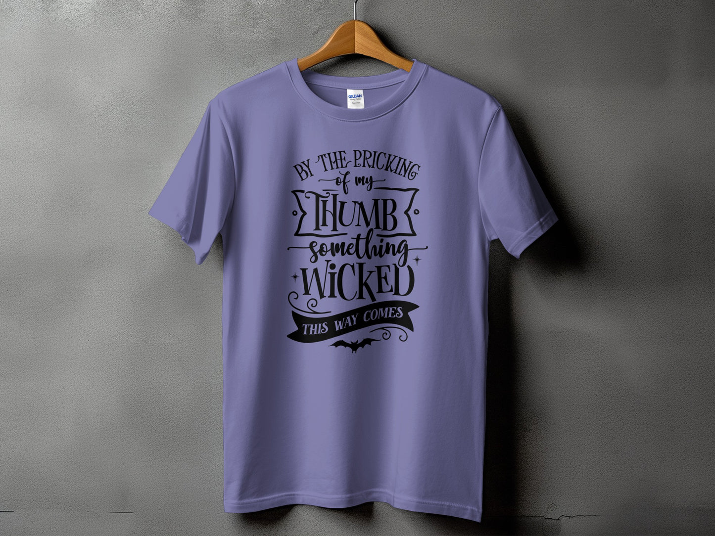 Lavender t-shirt with black text "By the pricking of my thumb something wicked this way comes".