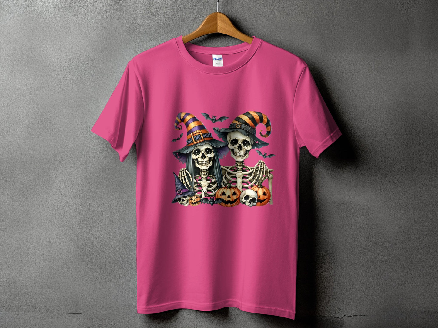 Pink t-shirt with Halloween skeletons, pumpkins, and bats graphic design.
