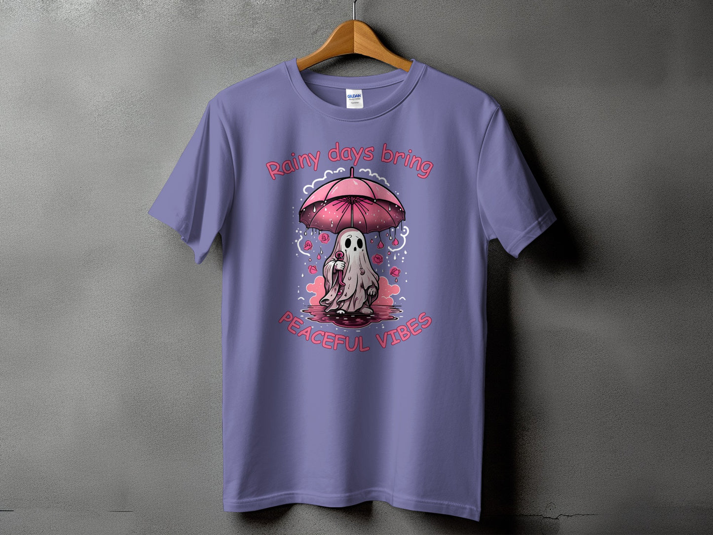 Purple t-shirt with a cartoon ghost holding an umbrella and text "Rainy days bring peaceful vibes".