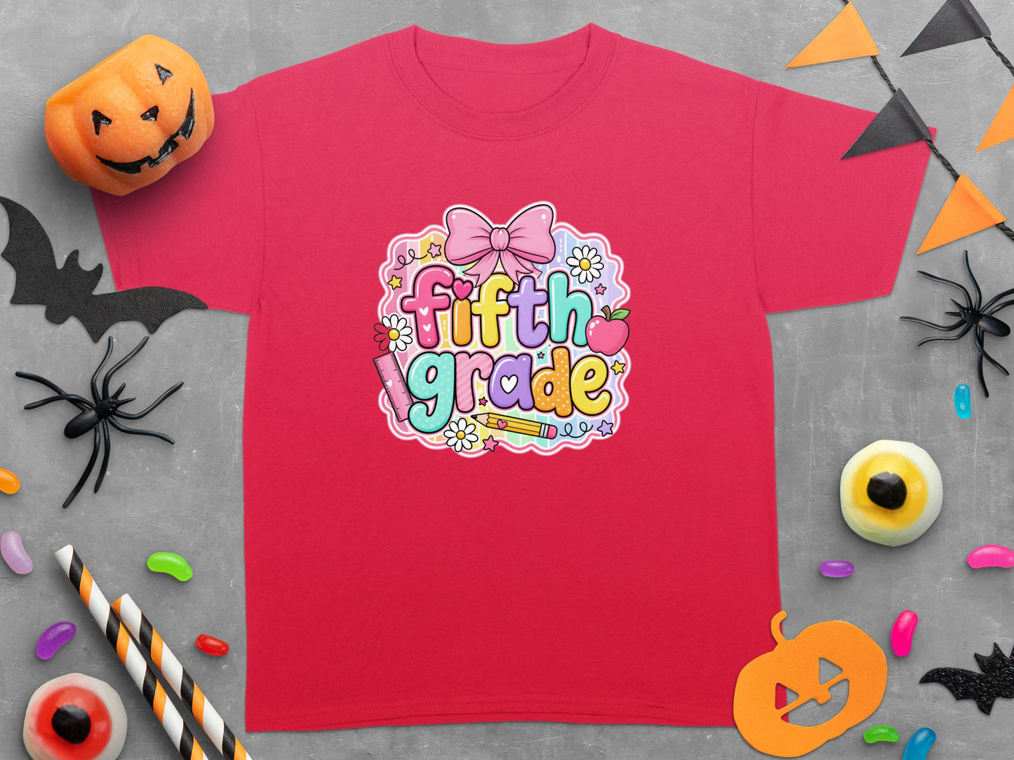 Red t-shirt with "fifth grade" text graphic surrounded by pastel shapes and Halloween decorations.