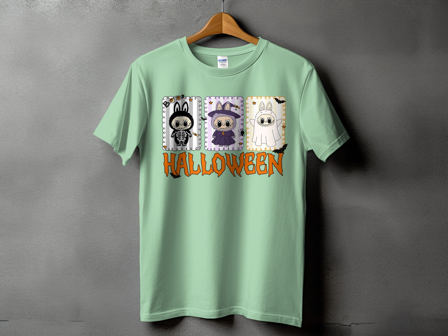Light green t-shirt with three cartoon Halloween characters and the word HALLOWEEN.