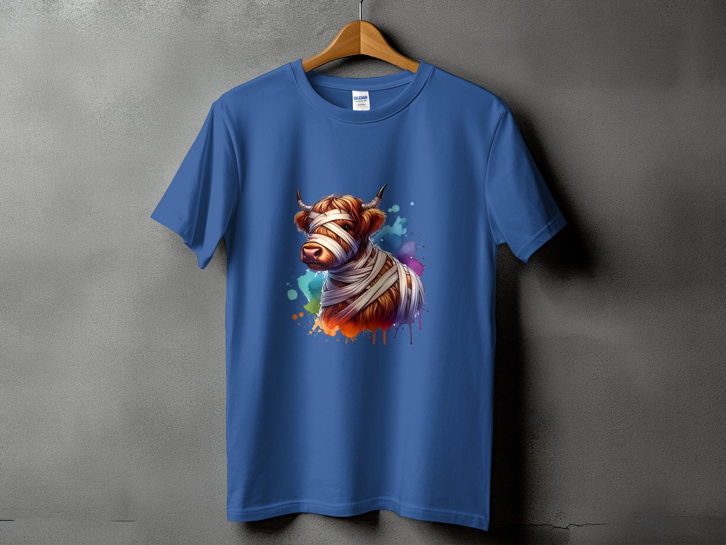 Blue t-shirt with a mummy Highland cow graphic and colorful paint splatters.