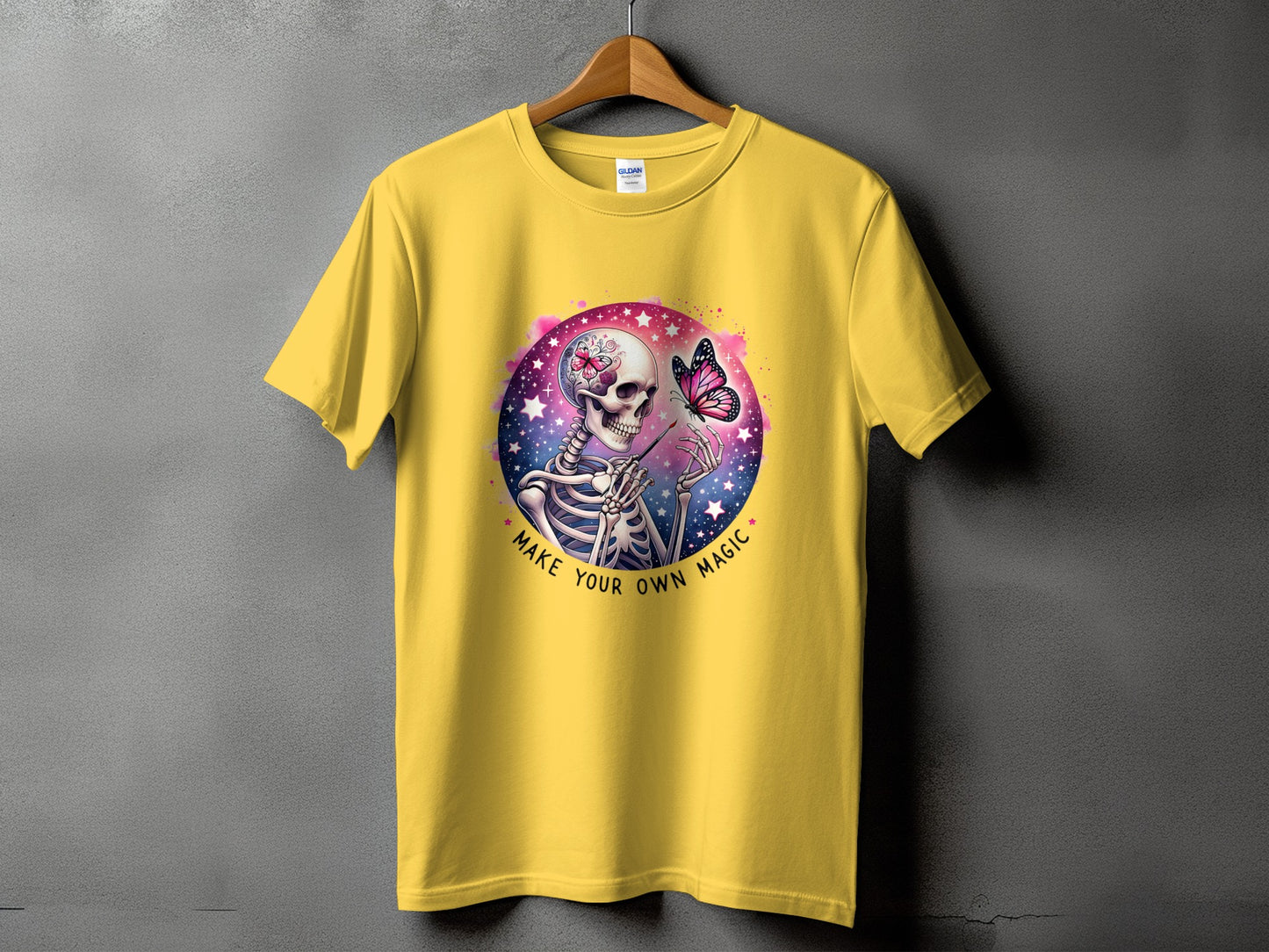 Yellow t-shirt with skeleton, butterfly, and text that says "Make Your Own Magic".