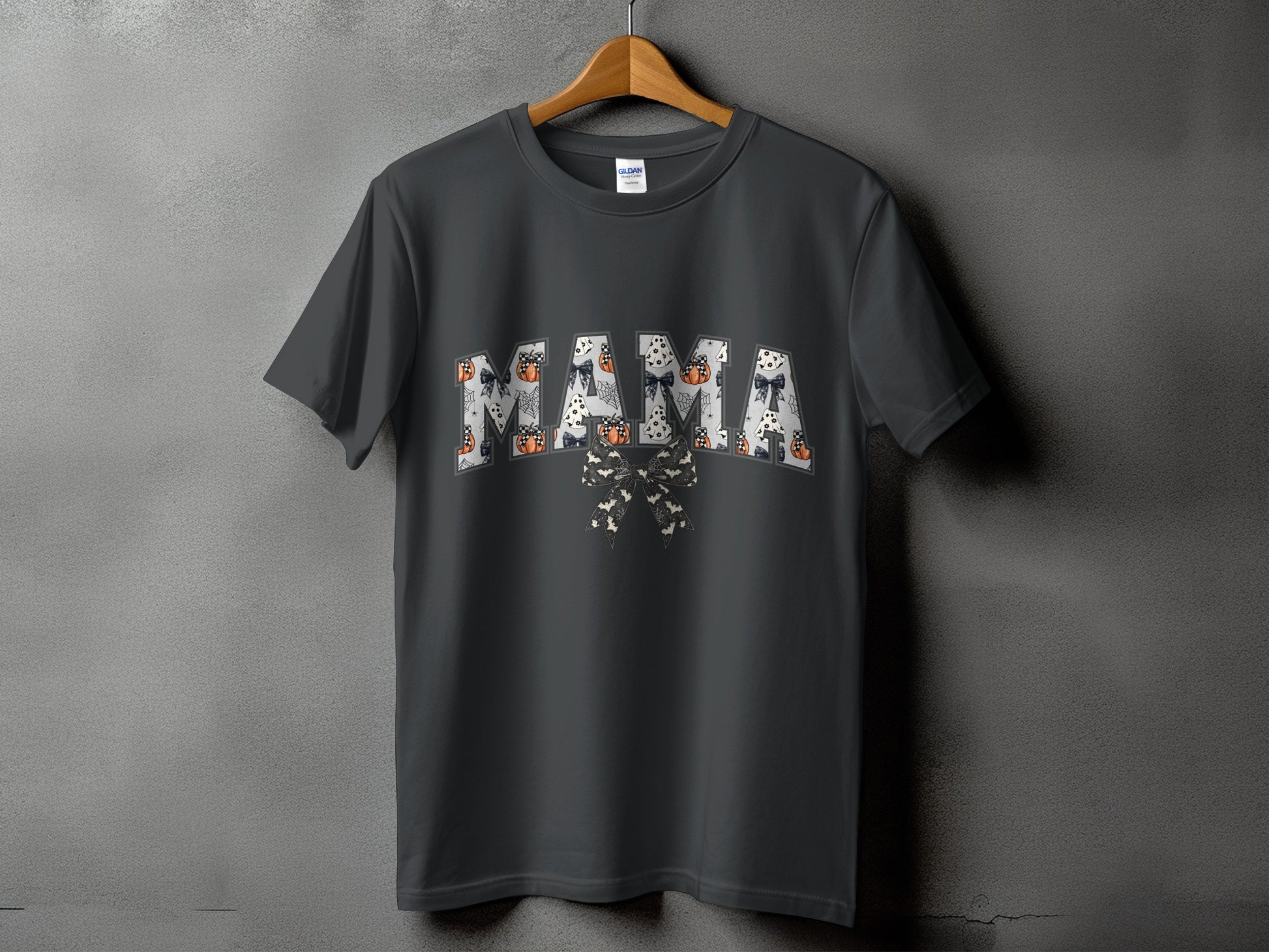 Dark grey t-shirt with arched "MAMA" text featuring Halloween patterns and a bow.