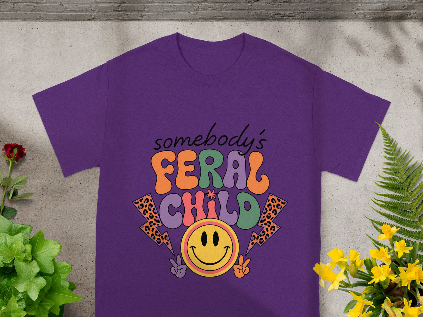 Purple t-shirt with "somebody's FERAL CHILD" text and smiley face graphic.