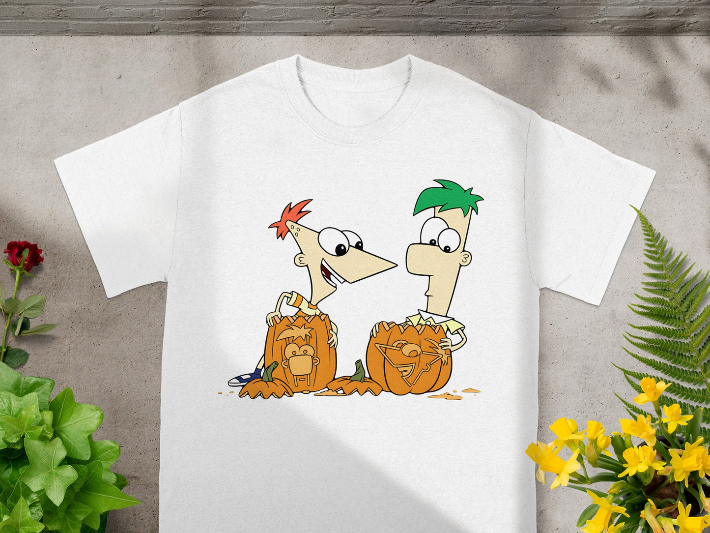 Phineas and Ferb characters carved into pumpkins on a white t-shirt.