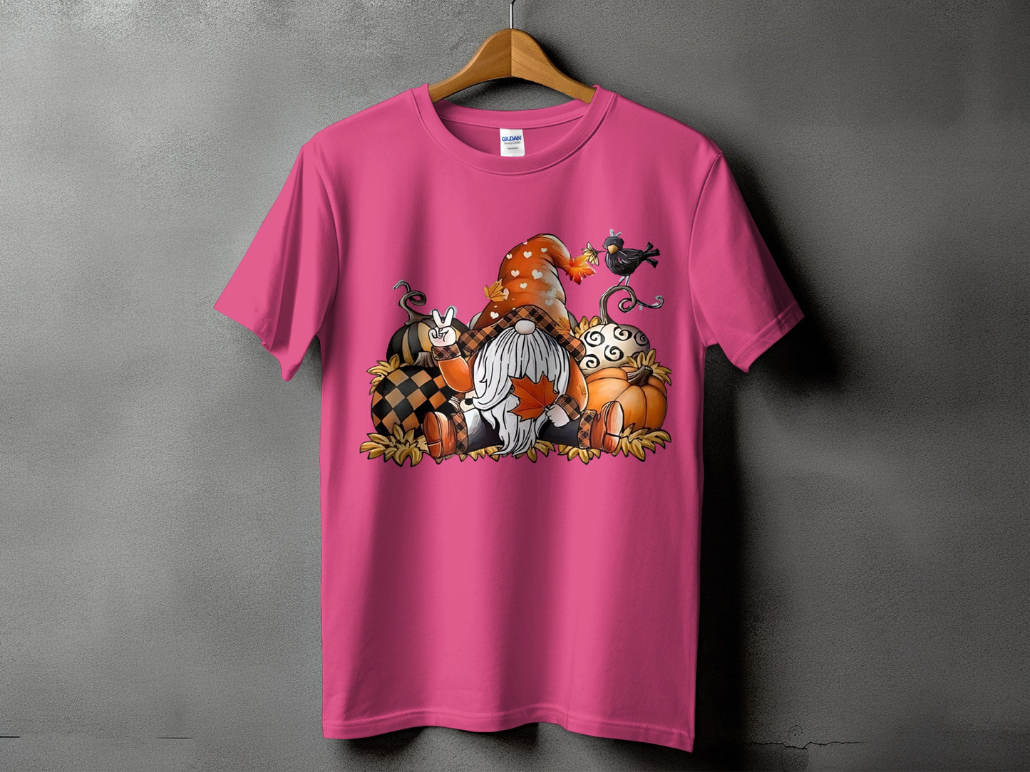 Gnome with pumpkins and leaves graphic on a pink t-shirt.