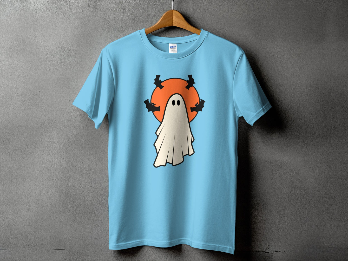 Light blue t-shirt with a cartoon ghost, orange moon, and bats.