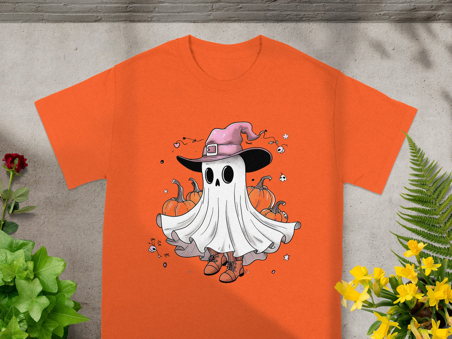 Orange t-shirt with a cartoon ghost wearing a pink witch hat and boots.
