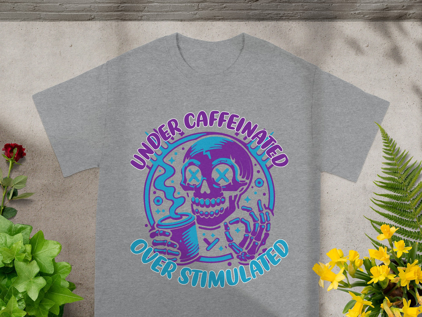 Gray t-shirt with purple and blue skull graphic holding coffee cup, reading "Under Caffeinated Over Stimulated".