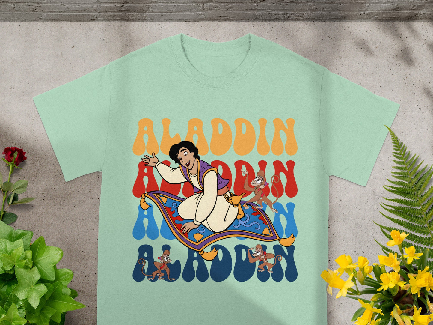 Aladdin and Abu ride a magic carpet with "Aladdin" text in colorful retro lettering.