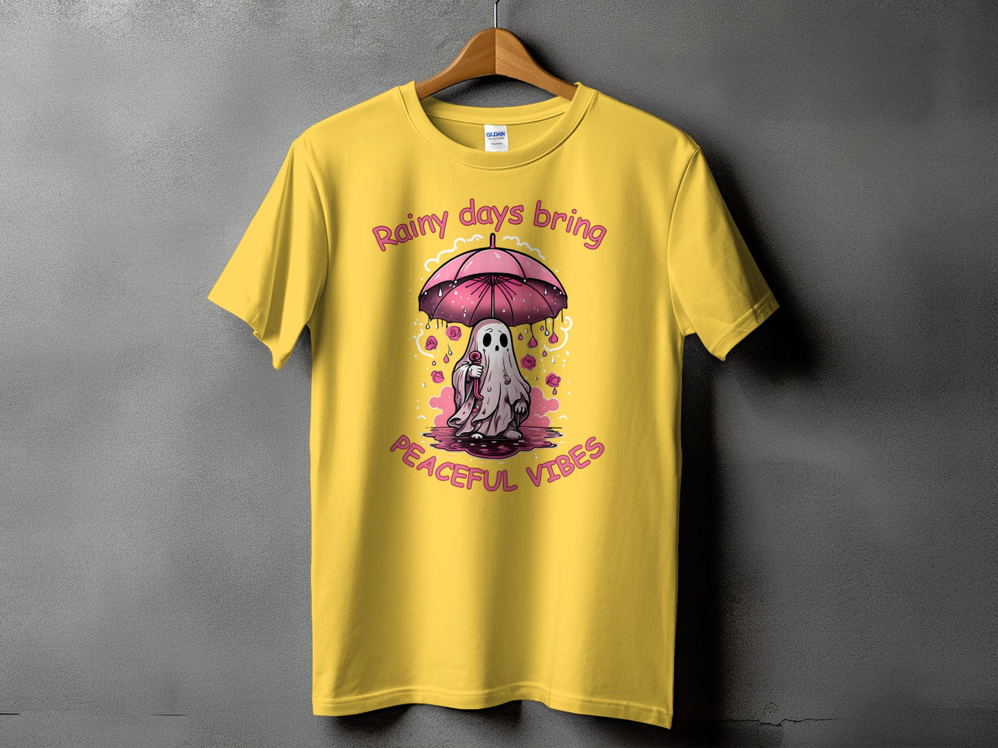Yellow t-shirt with a ghost holding an umbrella and text "Rainy days bring peaceful vibes".