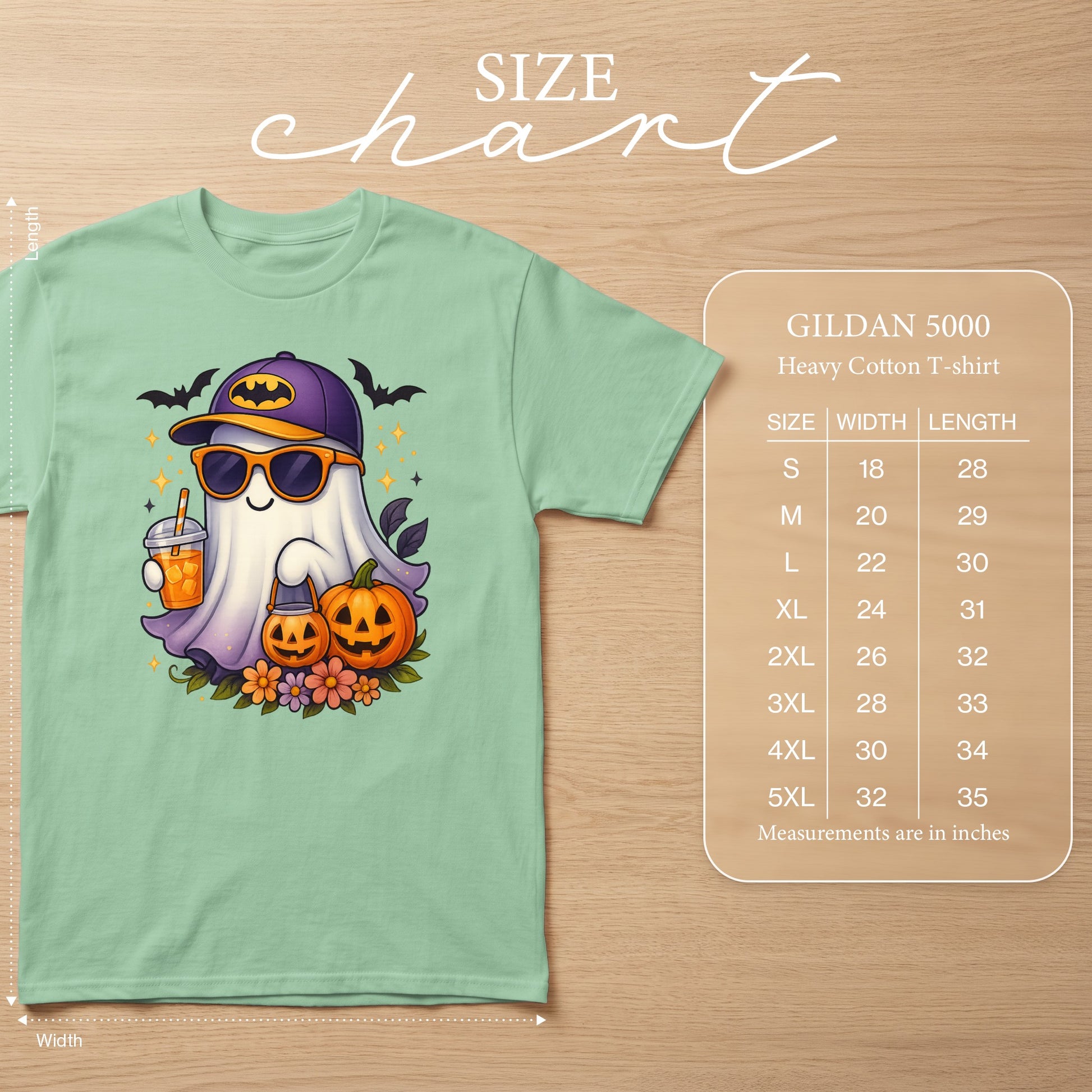 Mint green t-shirt with a cartoon ghost wearing a Batman hat and sunglasses, holding a drink and a pumpkin bucket.