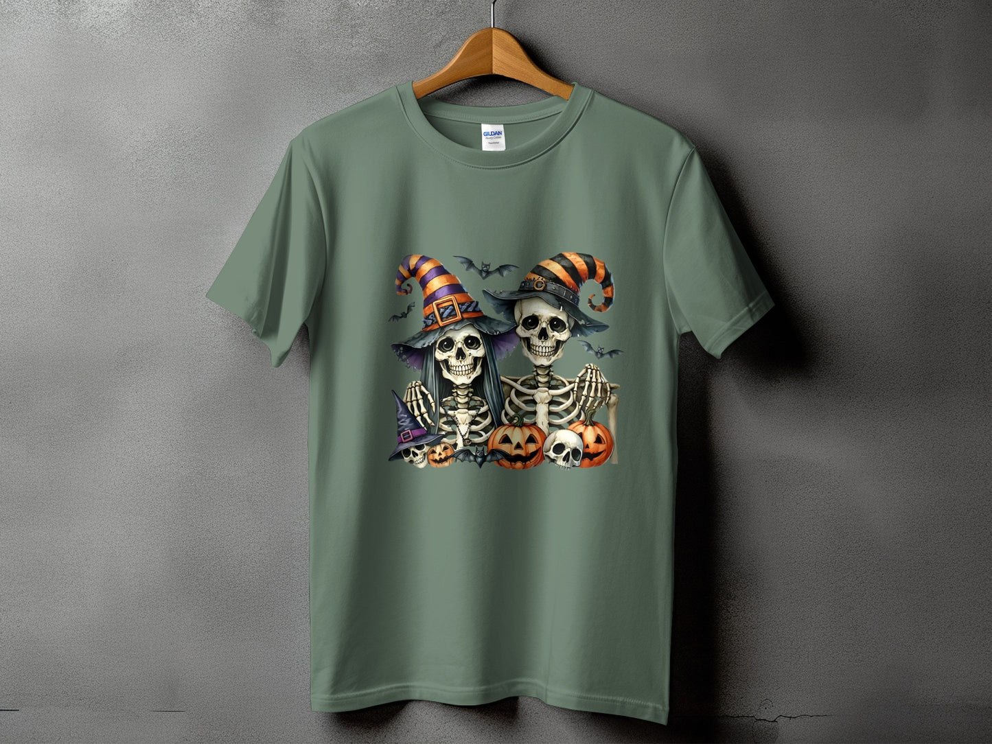 Green t-shirt with two skeletons wearing Halloween hats and holding pumpkins.