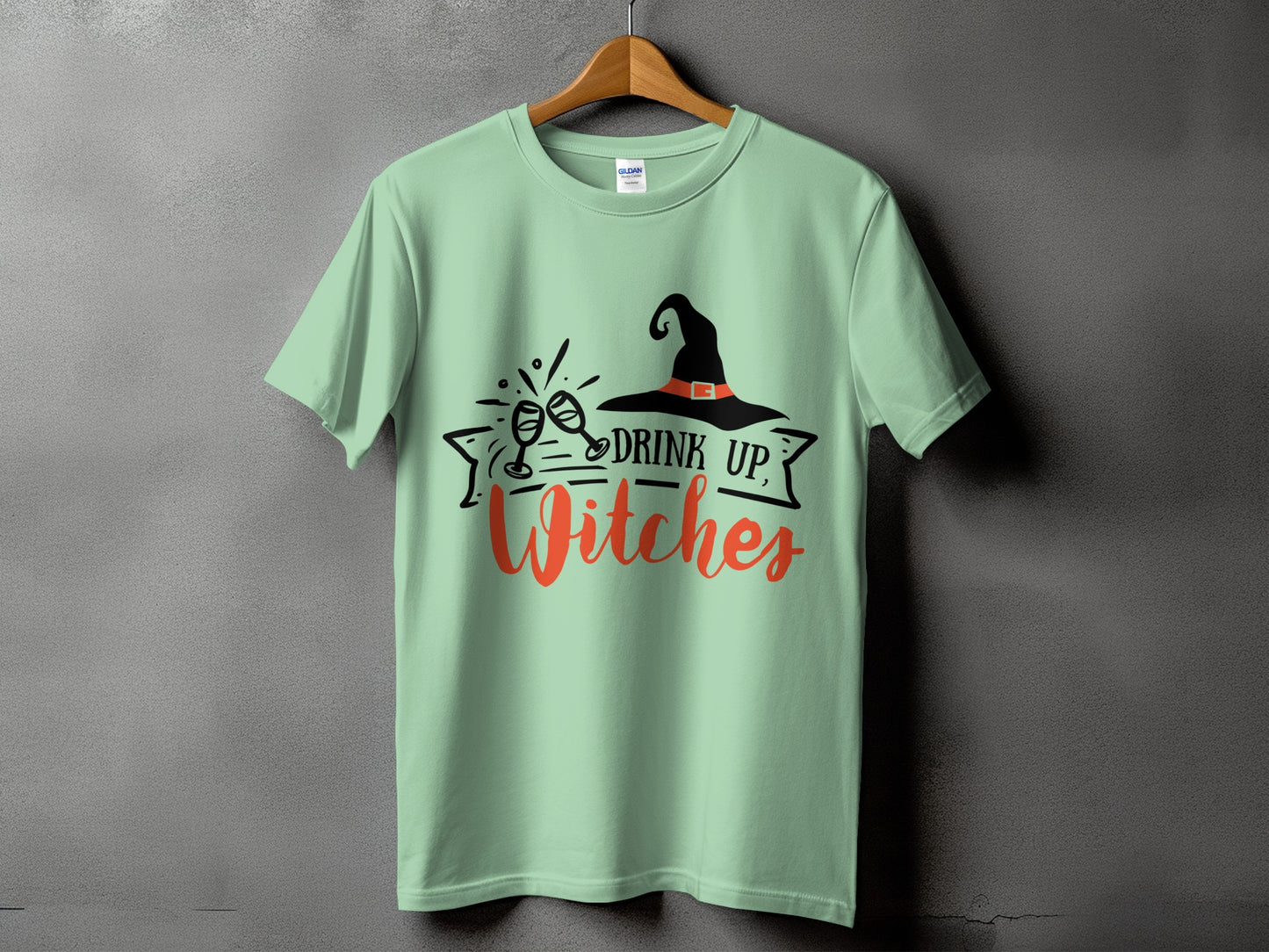 Light green t-shirt with black and orange "Drink Up, Witches" Halloween graphic.