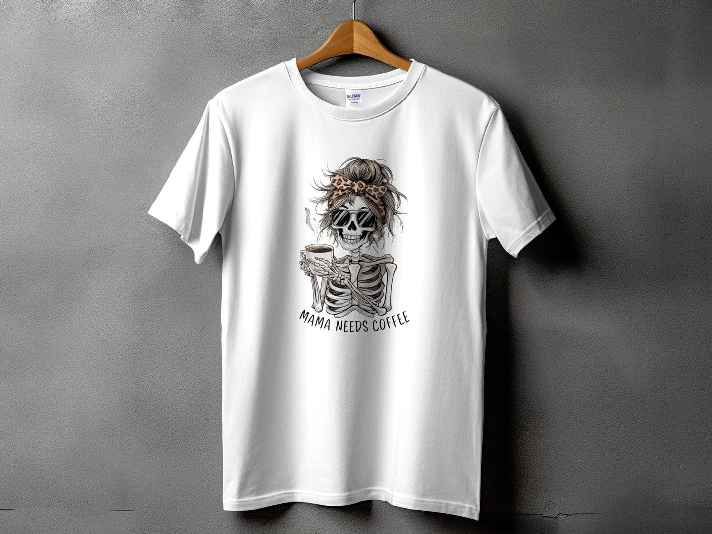 White t-shirt with skeleton graphic, leopard print bandana, sunglasses, and text "Mama Needs Coffee".