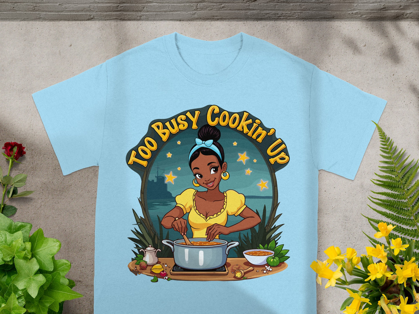 Light blue t-shirt featuring cartoon woman cooking with text "Too Busy Cookin' Up".