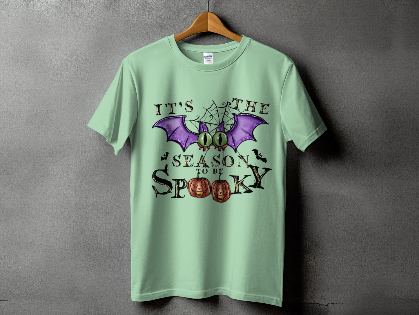 Light green t-shirt with "It's The Season To Be Spooky" Halloween graphic.