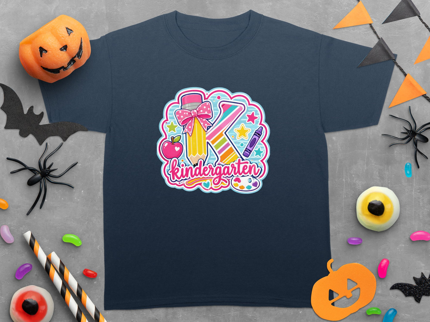 Dark blue t-shirt with a "K" graphic featuring a crayon, pencil, apple, and stars and the word "Kindergarten".