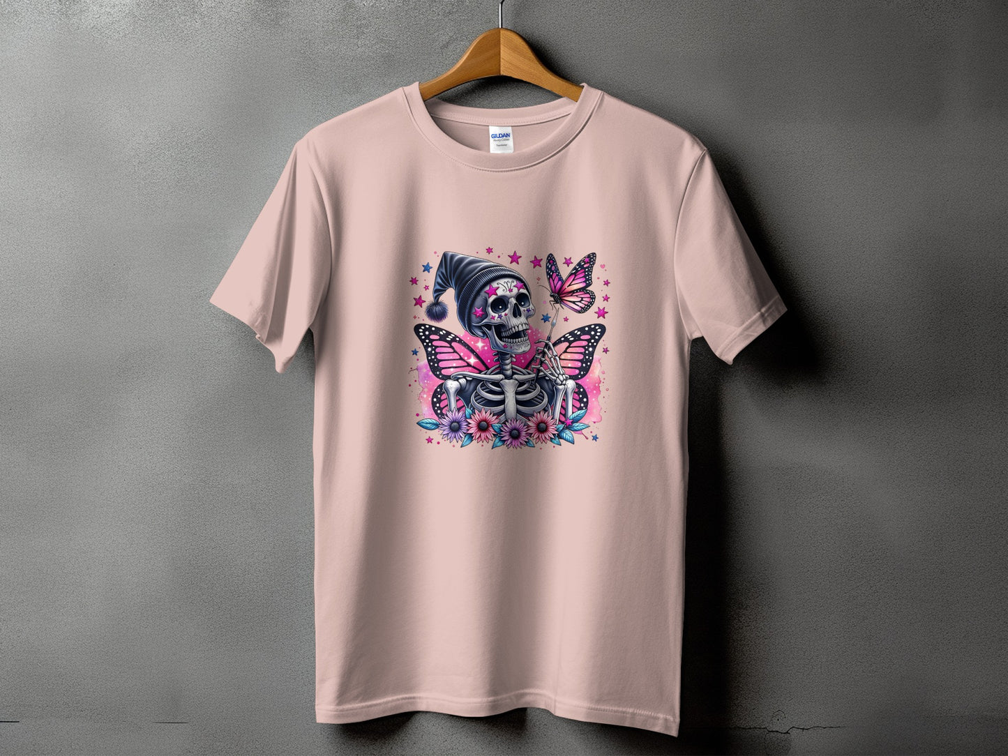 Pink t-shirt with a skeleton wearing a hat, butterflies, and flowers graphic.