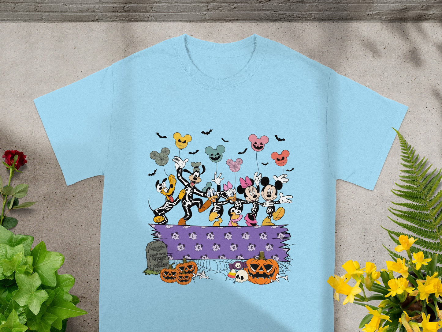 Mickey Mouse characters in skeleton costumes, Halloween balloons, pumpkins, and tombstone on a blue t-shirt.