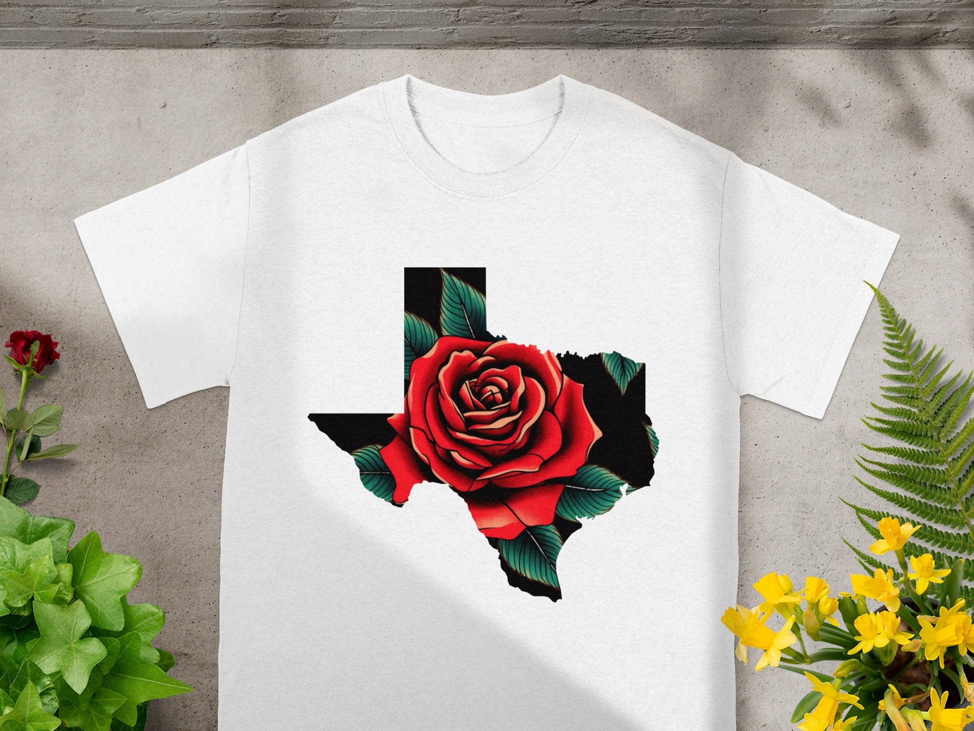 White t-shirt with Texas silhouette filled with a red rose and green leaves.