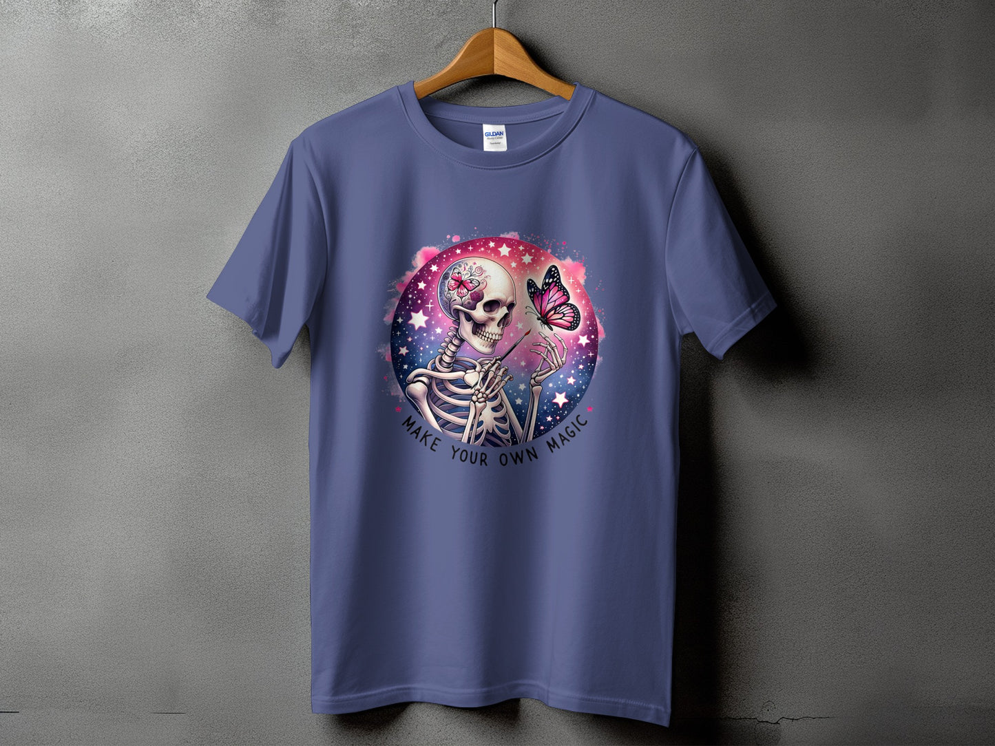 Skeleton with butterfly and paintbrush, "Make Your Own Magic" text, on purple t-shirt.