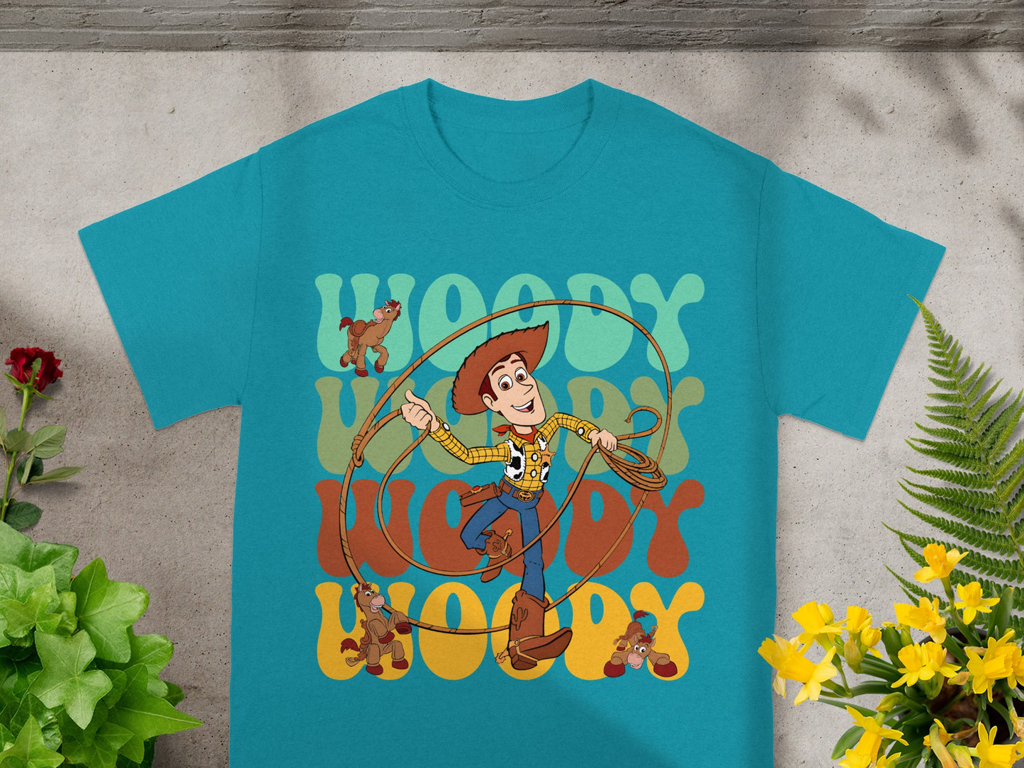 Woody from Toy Story on a teal t-shirt with "Woody" text and horse graphics.