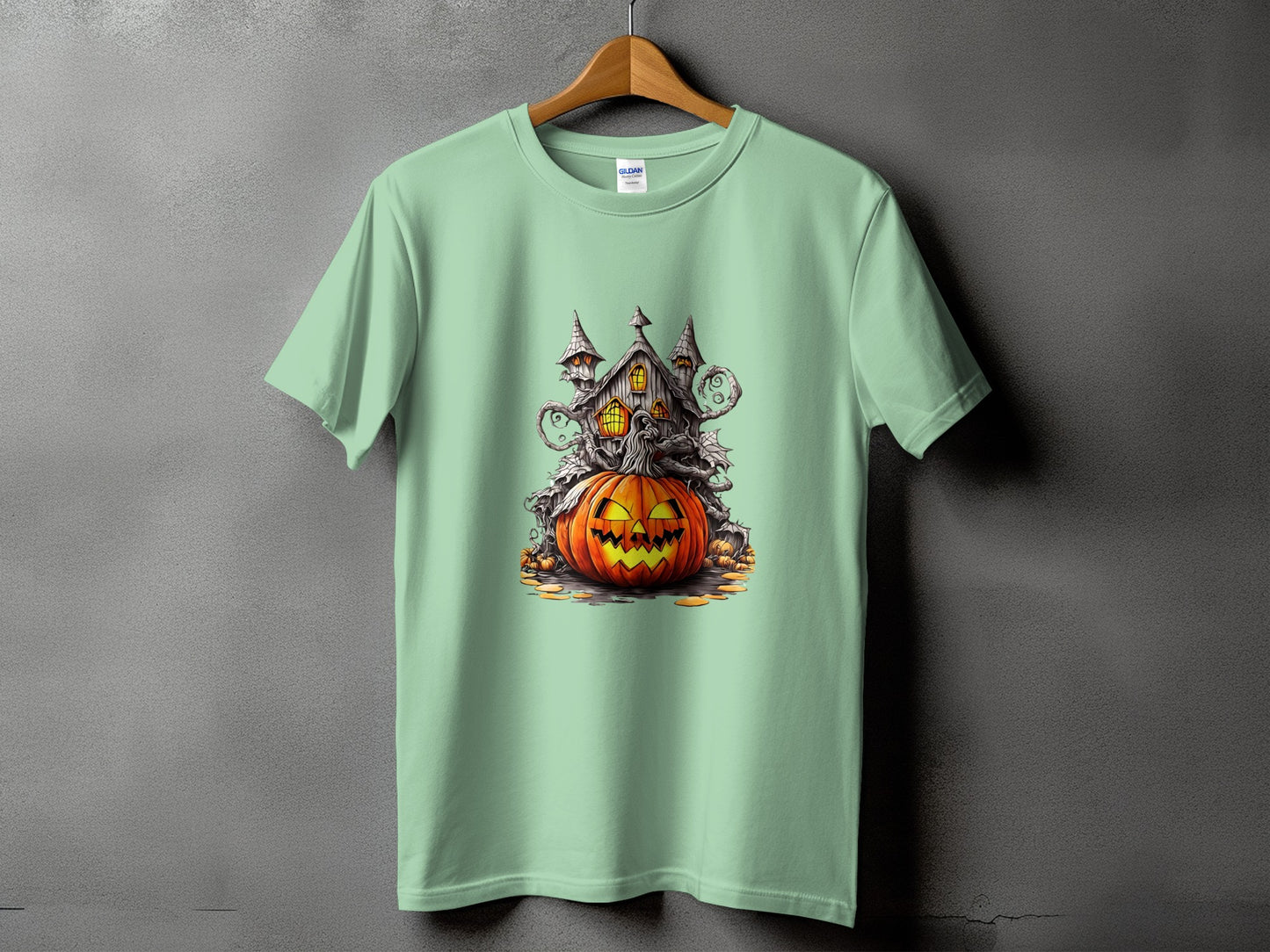 Light green t-shirt with a Halloween graphic of a jack-o'-lantern and haunted house.