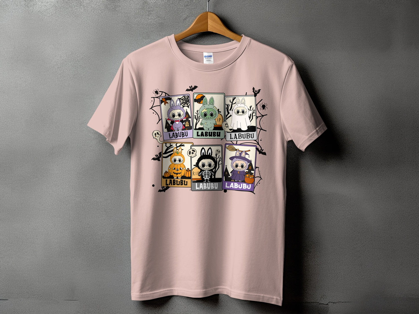 Pink t-shirt with six "Labubu" Halloween character squares and spiderweb graphics.