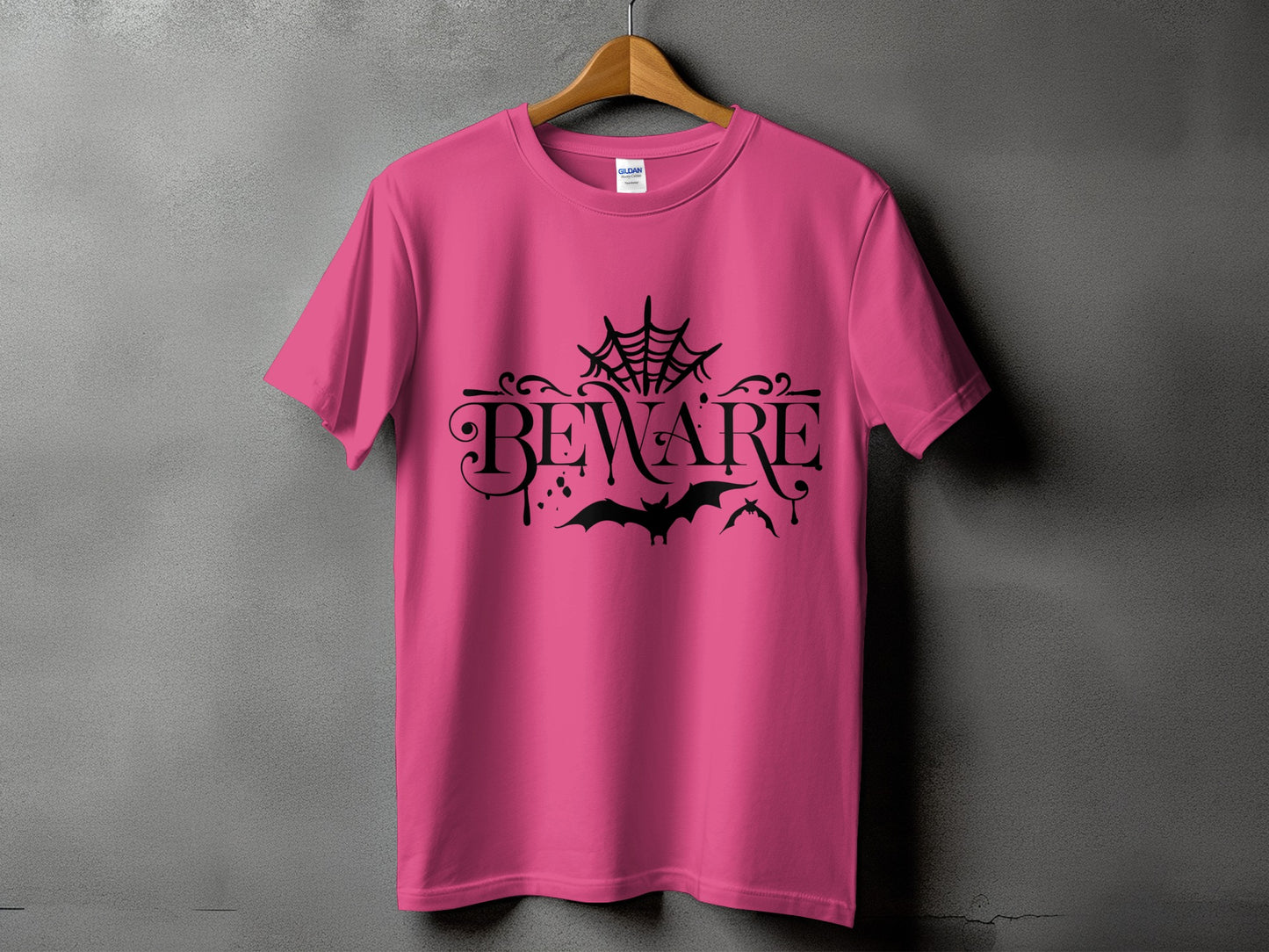 Pink t-shirt with black "BEWARE" text, spiderwebs, and bats design.