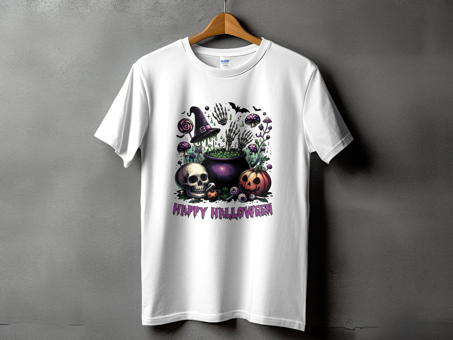 White t-shirt with a Halloween graphic featuring a cauldron, skull, pumpkin, and text.