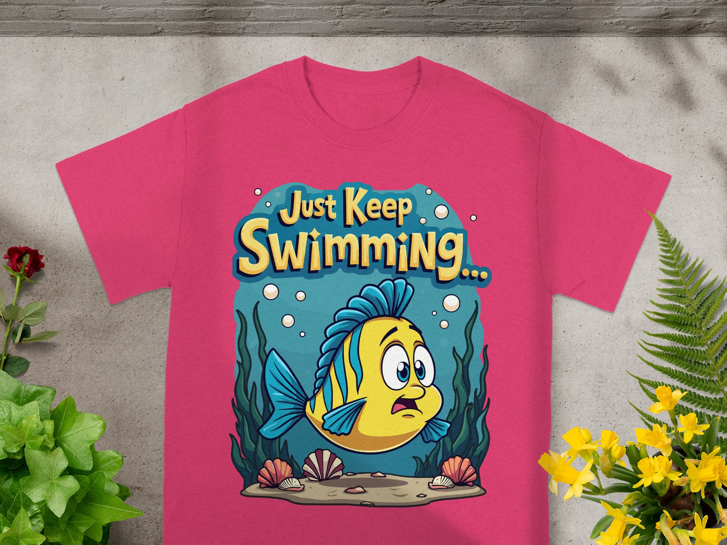 Pink t-shirt with a cartoon yellow fish and text "Just Keep Swimming...".