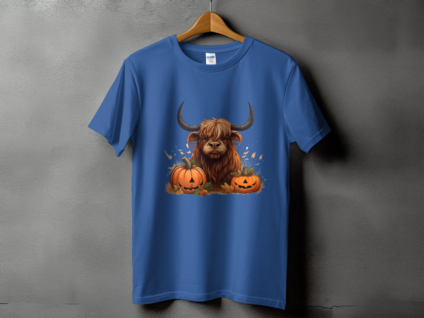 Highland cow with pumpkins graphic on a blue t-shirt.