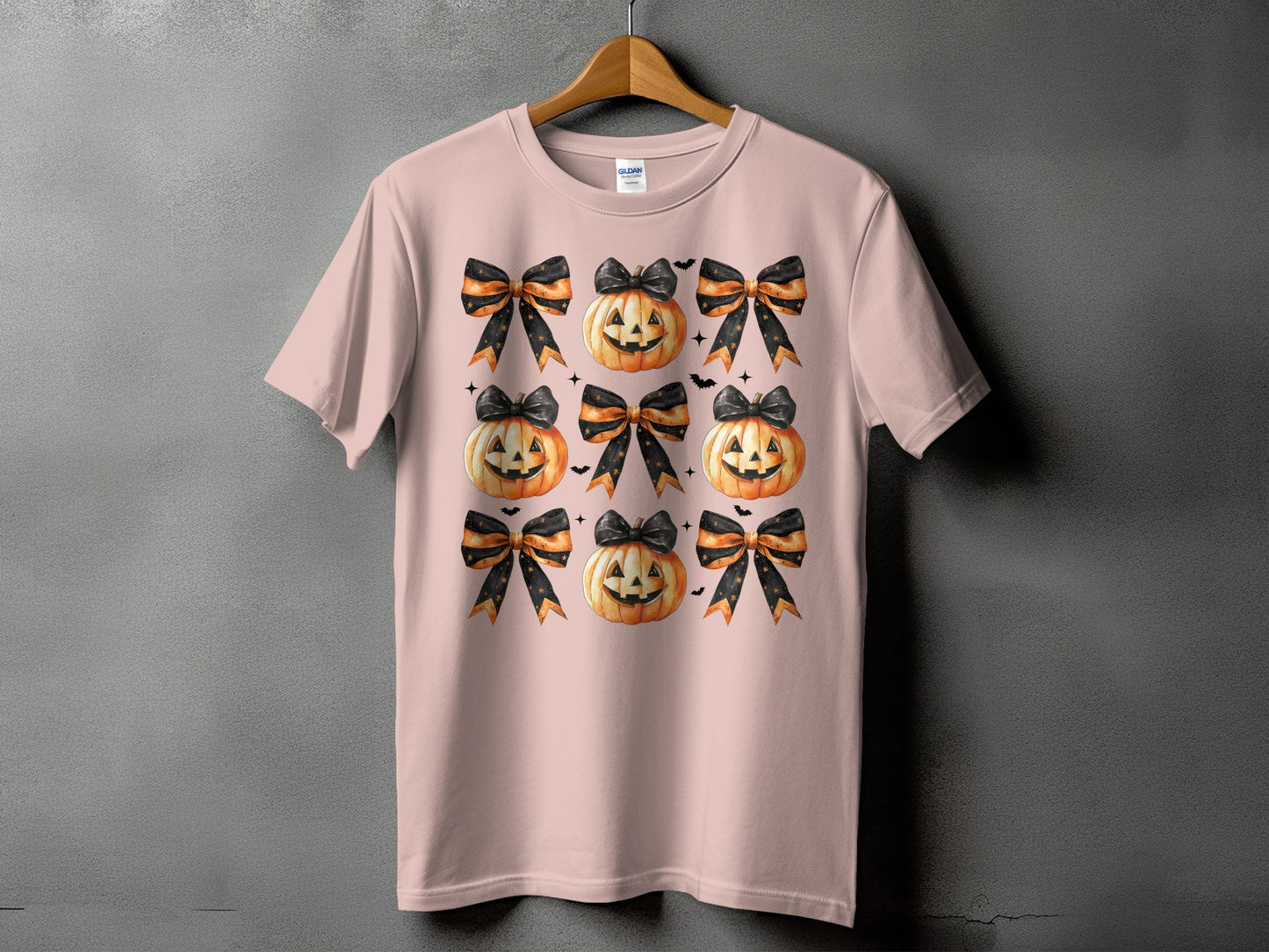 Pink t-shirt with a pattern of jack-o'-lanterns and black and orange bows.