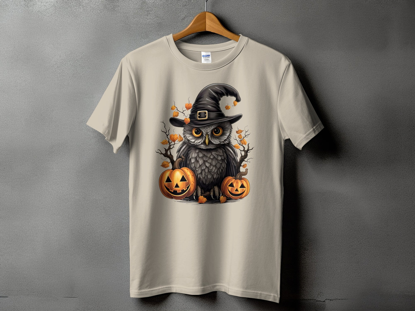 Owl with witch hat and pumpkins graphic on a light tan t-shirt.