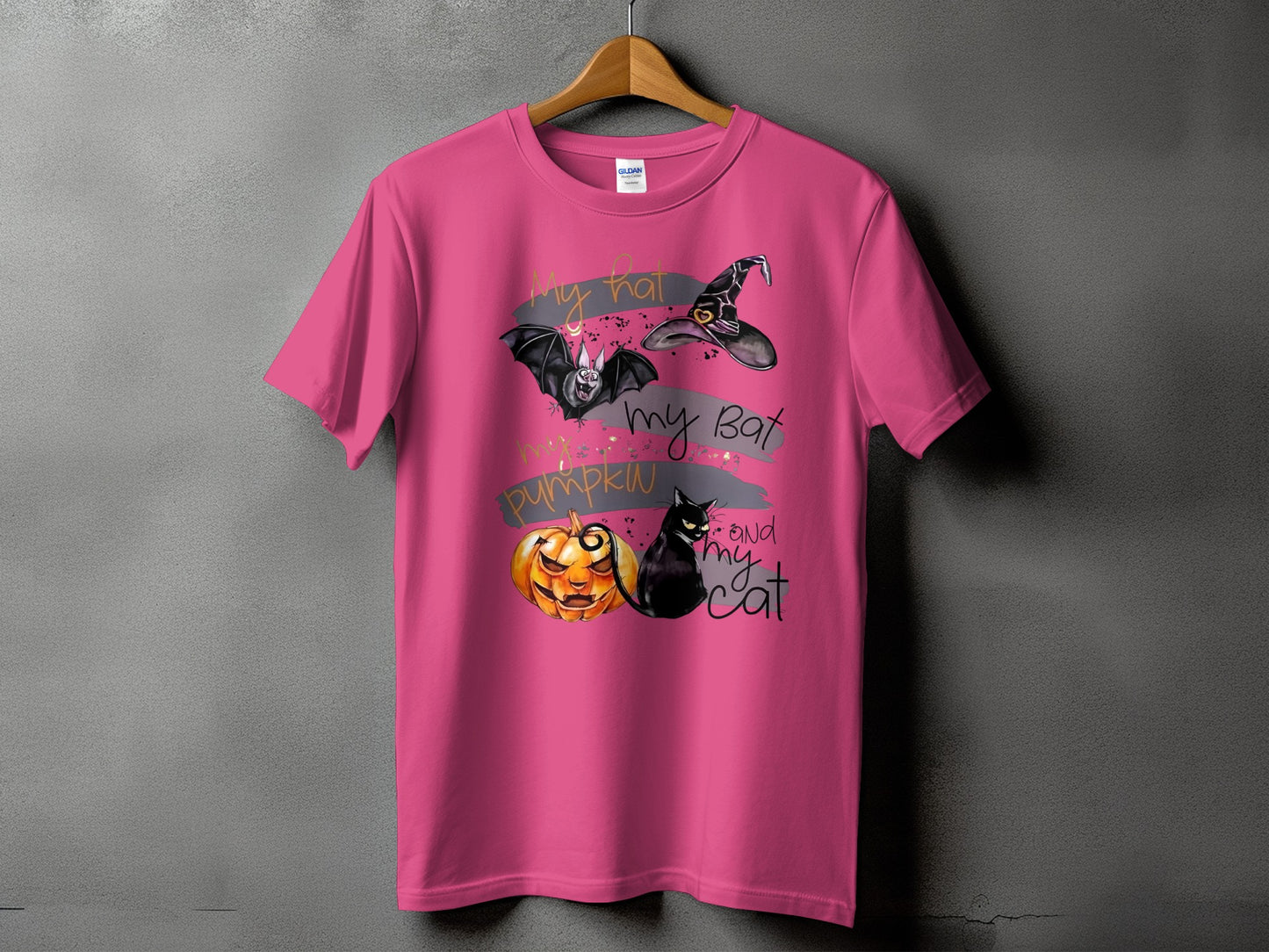 Pink t-shirt with Halloween graphic: bat, witch hat, jack-o'-lantern, and black cat with text.