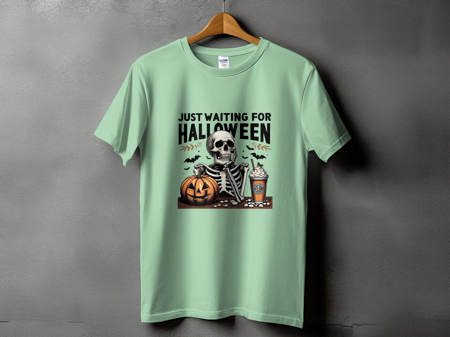 Light green t-shirt with skeleton, pumpkin, and coffee cup Halloween graphic and text.